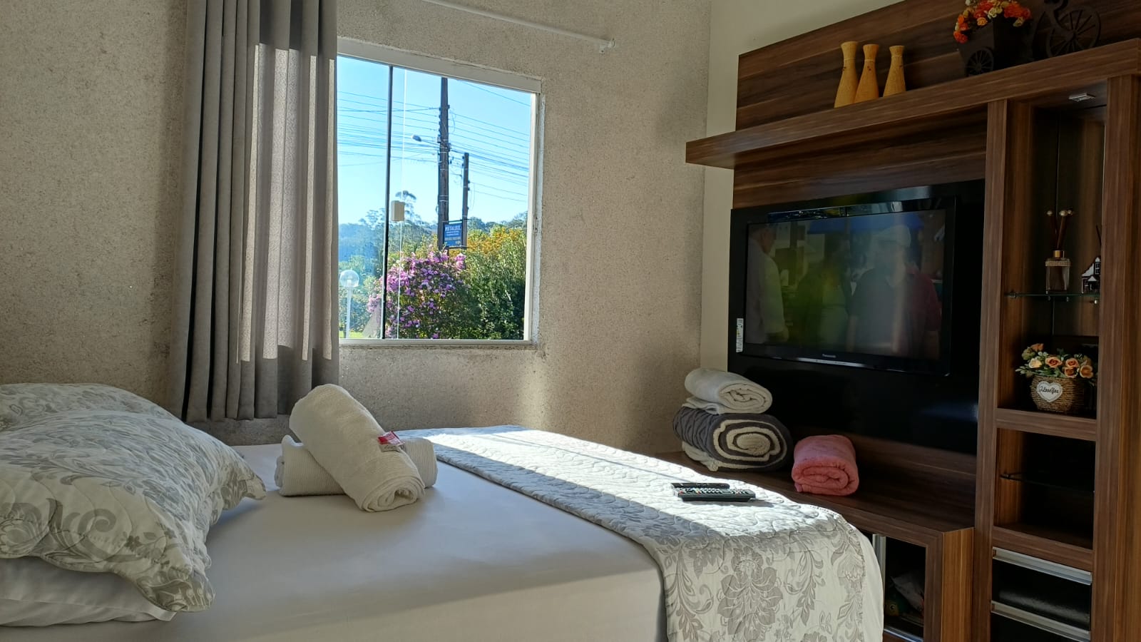 Quarto da suíte com TV e cama preparada para os hóspedes